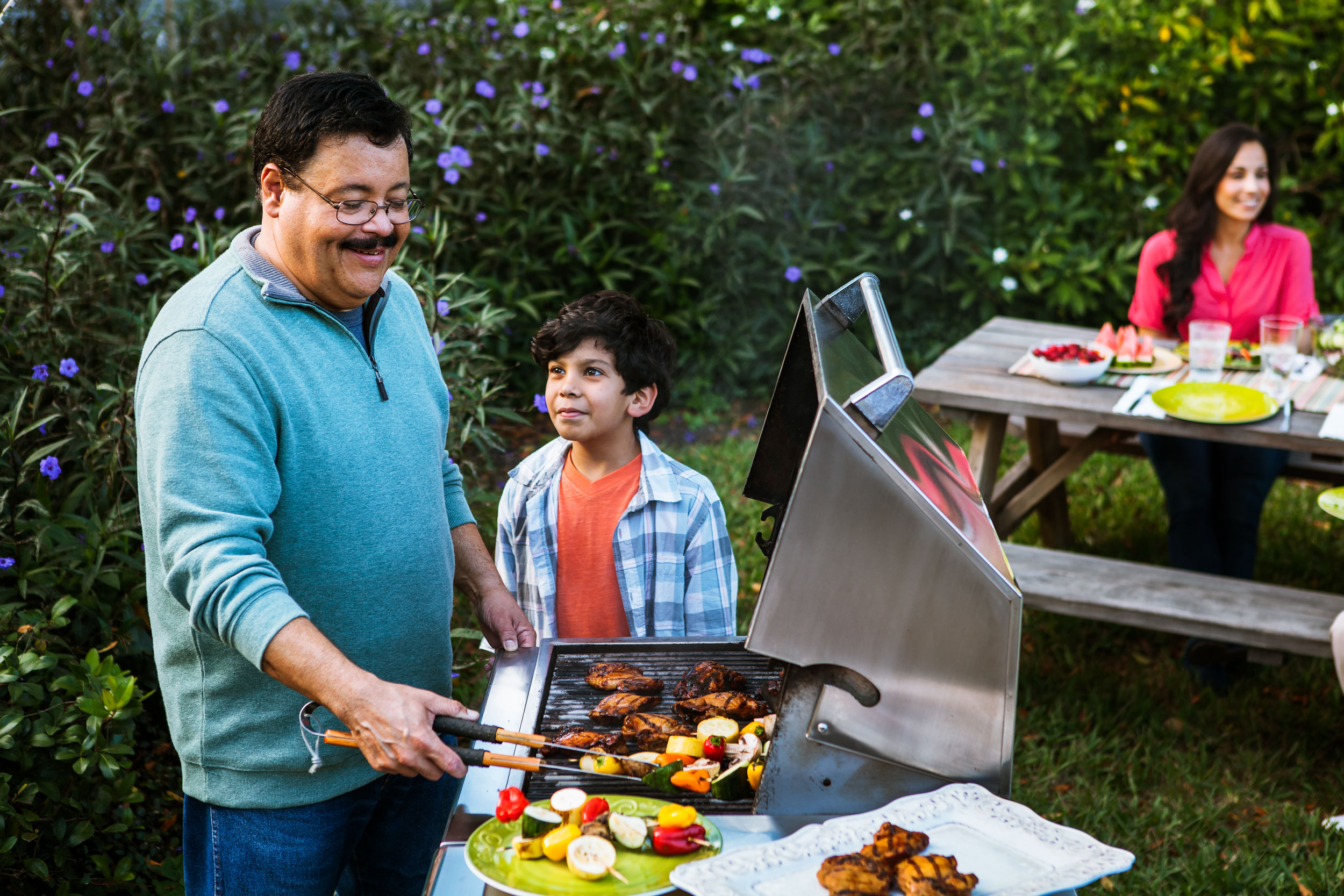 Lifestyle Photograph of Dad and Son at their Backyard Barbecue at Home by Michael Weschler